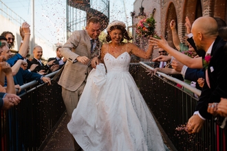 A couple who have just been married walk down an aisle and have confetti thrown at them 