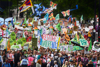 A procession of people with colourful signs saying restore nature now