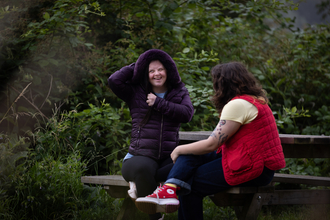 Two people sat at picnic bench in Walthamstow Wetlands