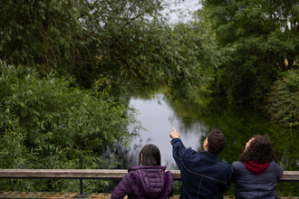 Three people looking over bridge at Walthamstow Wetlands