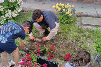 Lois communties and youth officer at London Wildlife Trust creating a wildlife garden with young people in Tower Hamlets, they dig flowers into a bed together.