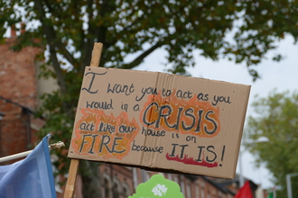 A homemade sign which reads: I want you to act as you would in a CRISIS act like our house is on FIRE because IT IS