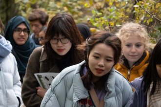 A group of young people gathered together holding wildlife identification material listening to a London Wildlife Trust staff member talk at Camley Street Natural Park.