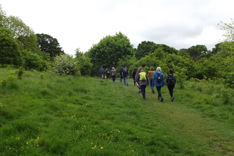 A group of people walking across a field with trees around