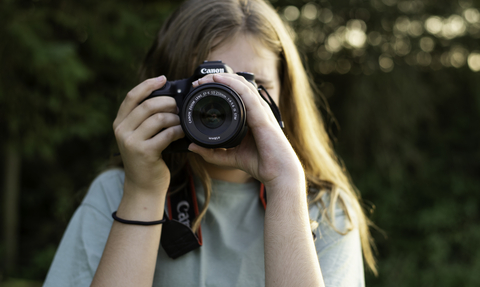 Person holding a camera up to their eye facing the viewer