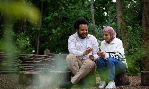 Two young people sat on a log in a woodland