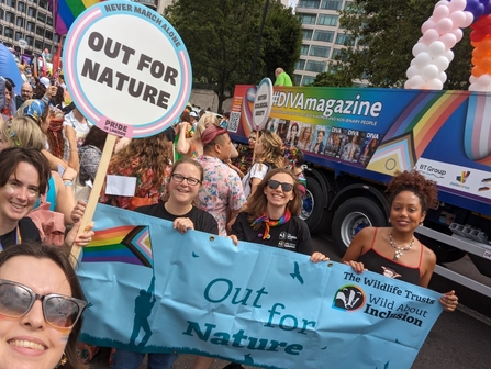 a group of people holding a loud banner that says out for nature