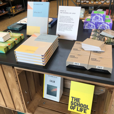 A selection of books, cards and games from the company The School of Life sit on a wooden display in the Walthamstow Wetlands nature reserve shop.