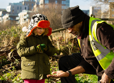 A child looking at a newt held in a persons hand