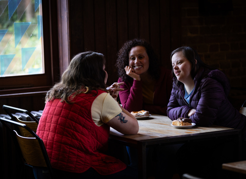 Three visitors sitting at a table eating pastries and drinking coffee at the Engine House Café, Walthamstow Wetlands.